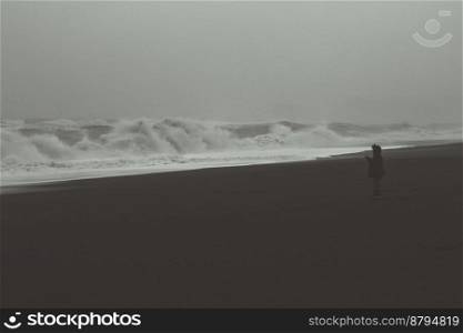 Person at stormy seaside monochrome landscape photo. Beautiful nature scenery photography with sky on background. Idyllic scene. High quality picture for wallpaper, travel blog, magazine, article. Person at stormy seaside monochrome landscape photo