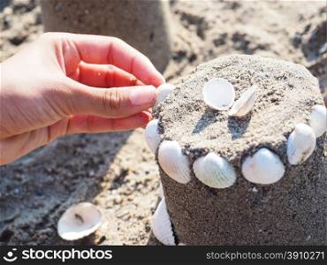 Person creating a sand castle with white clams