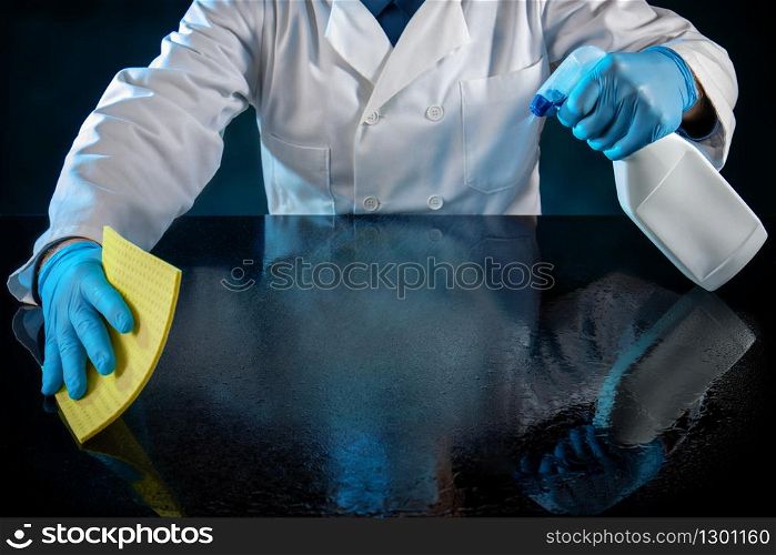 Person dressed in white uniform spraying a table with anti virus solution