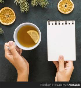 person drinking tea holding empty notebook