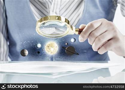 Person exploring planets of space. Close view of businessperson exploring space planets with magnifying glass