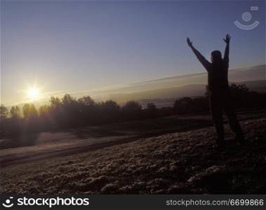Person Greeting Sunrise With Arms Raised