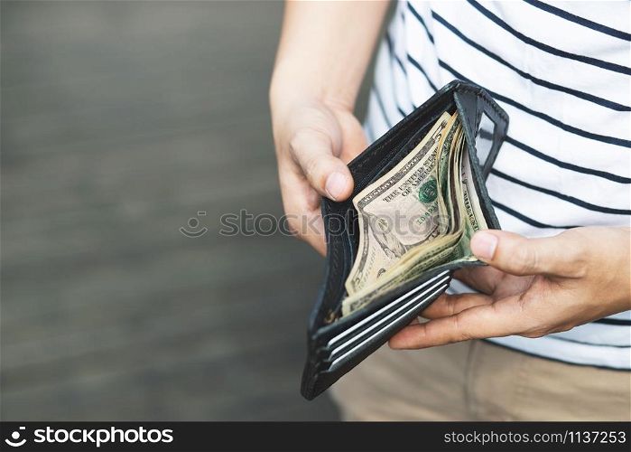 Person holding an wallet in the hands of an man take money out of pocket.