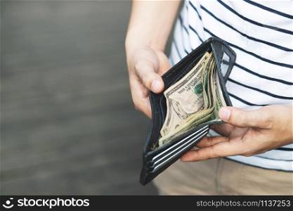 Person holding an wallet in the hands of an man take money out of pocket.
