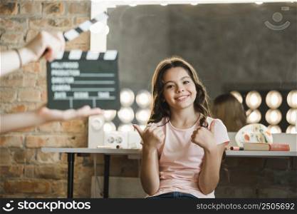 person holding clapper board front girl showing thumb up sign