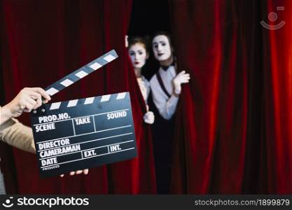 person holding clapperboard front mime couple standing red curtain. Resolution and high quality beautiful photo. person holding clapperboard front mime couple standing red curtain. High quality beautiful photo concept