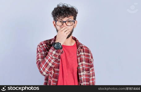 Person holding his nose looking at camera, people holding his nose with unpleasant smell expression, young man with bad smell expression holding his nose