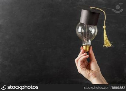 person holding light bulb with graduation cap. Resolution and high quality beautiful photo. person holding light bulb with graduation cap. High quality beautiful photo concept