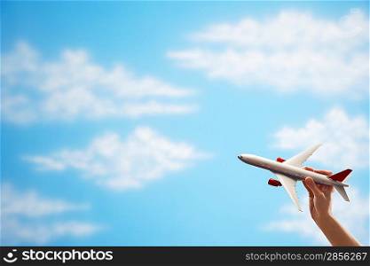 Person holding model airplane against sky