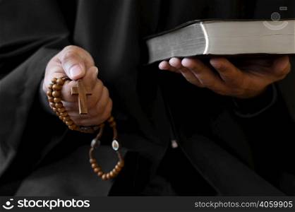 person holding rosary with cross holy book