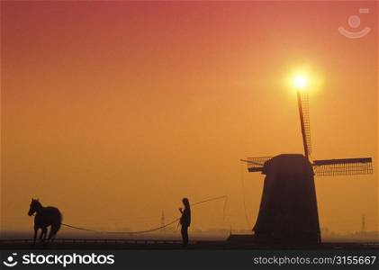 Person Horse and Windmill at Sunset