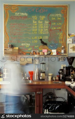 Person in shop with coffee prices on board