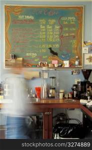 Person in shop with coffee prices on board