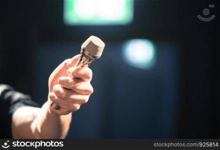 Person is holding up a metal microphone and wants to interview someone, copy space