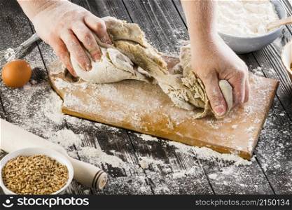 person kneading dough with flour chopping board