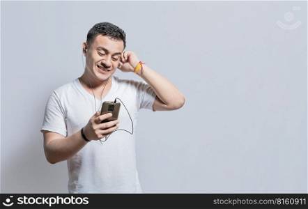 Person listening to music with his cell phone with headphones isolated, Handsome man enjoying music with headphones isolated, cheerful guy listening to music with his cell phone isolated