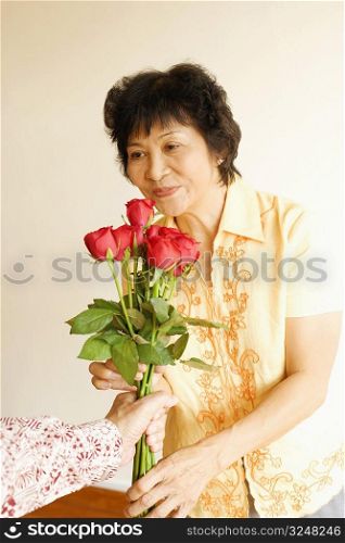 Person offering a bunch of roses to a mature woman