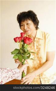 Person offering a bunch of roses to a mature woman