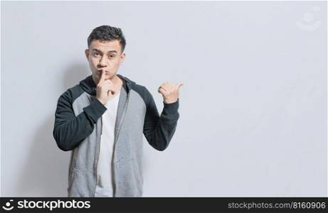 Person pointing to the side giving an offer isolated, people with finger on lip pointing to the side, Handsome man with finger on lip pointing to the side on isolated background