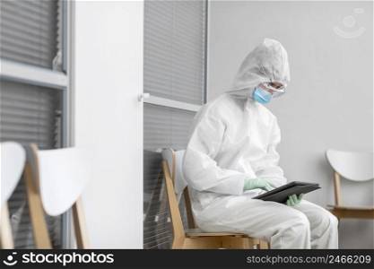 person protective suit looking tablet