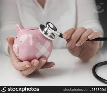 person putting stethoscope piggy bank