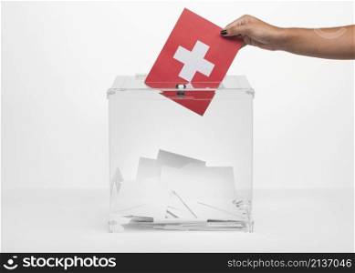 person putting switzerland flag card into ballot box