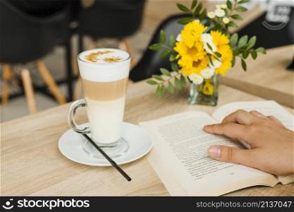 person reading book near coffee cup desk caf