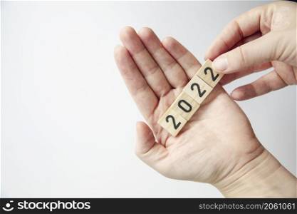 Person&rsquo;s hand holding 2022 on white background top view a minimal concept with copy space. Happy new year space for text. Person&rsquo;s hand holding 2022 on white background top view a minimal concept with copy space. Happy new year