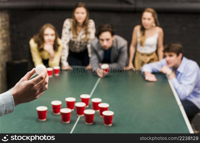 person s hand aiming ball beer pong game