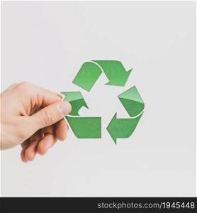 person s hand holding green recycle symbol white backdrop. High resolution photo. person s hand holding green recycle symbol white backdrop. High quality photo