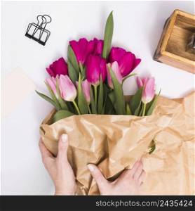 person s hand making tulip flowers bouquet with brown paper isolated white background