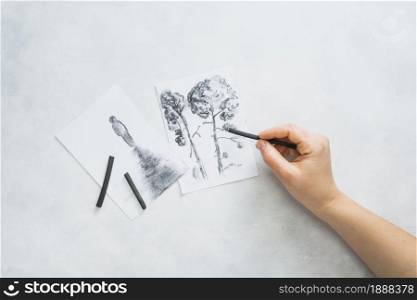 person s hand sketching beautiful drawing with charcoal stick white surface . Resolution and high quality beautiful photo. person s hand sketching beautiful drawing with charcoal stick white surface . High quality and resolution beautiful photo concept