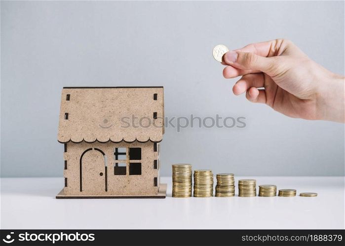 person s hand stacking coins near house model . Resolution and high quality beautiful photo. person s hand stacking coins near house model . High quality and resolution beautiful photo concept