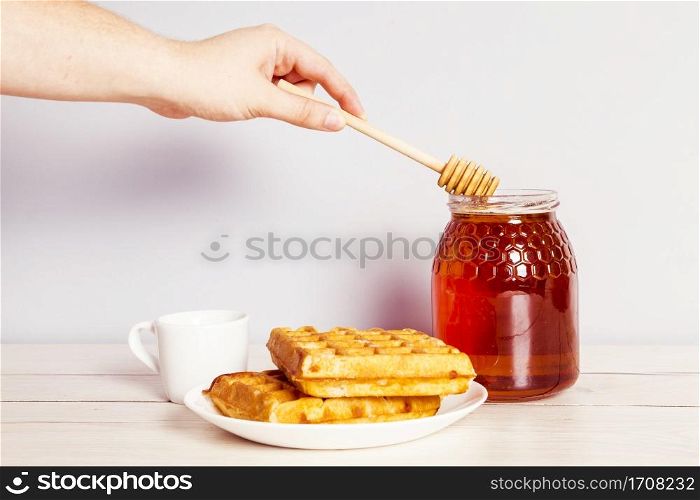 person s hand with dipper picking honey from jar breakfast