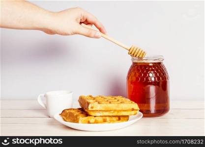 person s hand with dipper picking honey from jar breakfast
