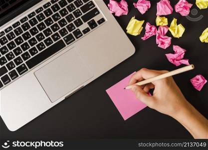person s hand writing with pencil adhesive note black background