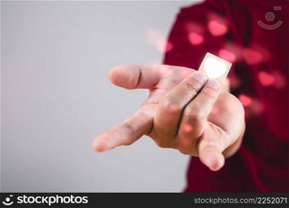 Person shows hands sign of love with heart visual effect. The man with red shirt in medium close up shot. Valentine&rsquo;s concept. Copy space for messages, words and texts.