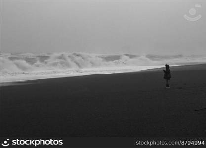 Person silhouette on coast monochrome landscape photo. Beautiful nature scenery photography with waves on background. Idyllic scene. High quality picture for wallpaper, travel blog, magazine, article. Person silhouette on coast monochrome landscape photo