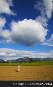 Person Standing In Field Under Cloud