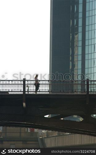 Person standing on a bridge next to a high rise building in Chicago