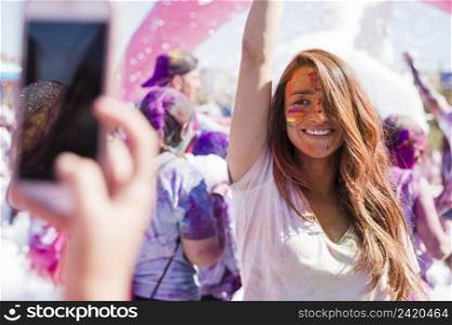 person taking selfie her smiling female friend mobile phone during holi