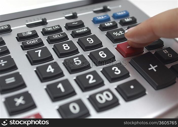 Person using calculator, close-up of finger