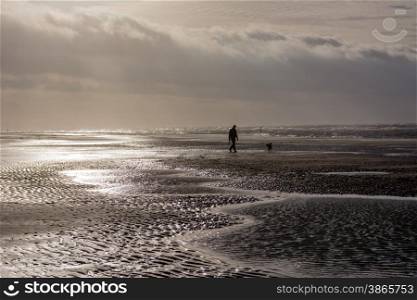 person walking dog at stormy day at beach