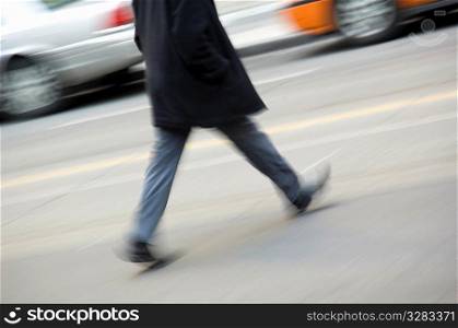 Person walking quickly across busy road.