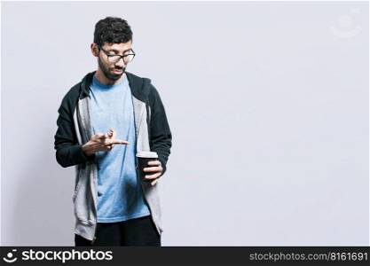 Person with coffee on isolated background, guy pointing disposable cup of coffee on isolated background, concept of a man showing looking at disposable cup of coffee