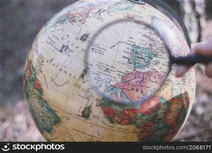 person with magnifying glass looking globe