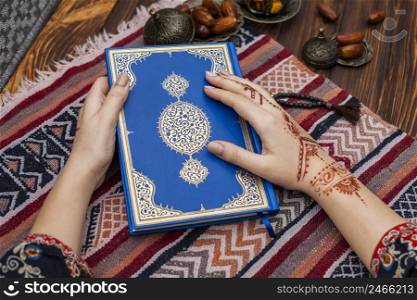 person with mehndi holding quran near dates fruit
