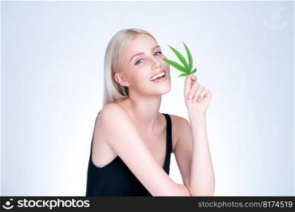 Personable beautiful white blond hair with perfect smooth makeup skin hold cannabis green hemp in isolated background for natural CBD skincare treatment with expressive facial and gesture expression.. Personable white blond hair woman holding CBD leaf in isolated background.