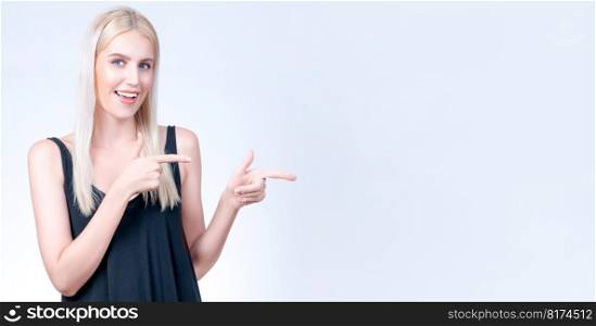 Personable beautiful woman with perfect makeup clean skin pointing finger in copyspace isolated background. Promotion indicated by hand gesture to show skincare product advertising.. Personable woman pointing finger advertising product in isolated background.