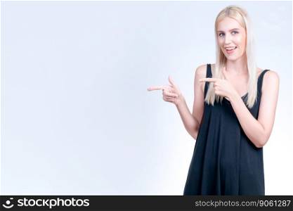 Personable beautiful woman with perfect makeup clean skin pointing finger in copyspace isolated background. Promotion indicated by hand gesture to show skincare product advertising.. Personable woman pointing finger advertising product in isolated background.